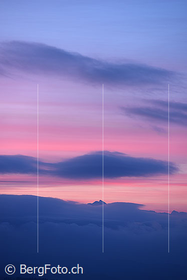 Foto: Zart gefärbter Morgenhimmel über dem Emmental. Aus den Wolken ragt der Gipfel der Jungfrau.
