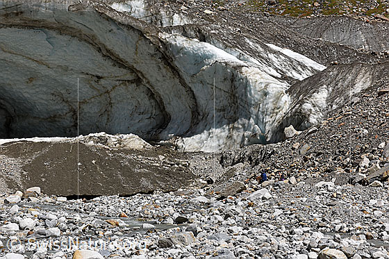 Photo: Unteraar Glacier: Northern glacier gate (as of July 2021). Two people are sitting in front of the glacier gate.