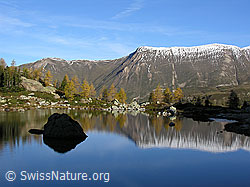 F030586: Glatter See, in welchem sich Felsblock und Bergkette spiegeln