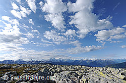 F068647: Wolkenhimmel über Hochebene mit Felsblöcken und Aussicht auf Berner Alpen