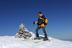 F074564: Skitourenfahrerin neben Steinmann auf dem Gipfel